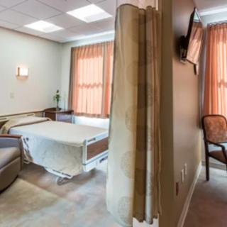 A hospital room with a bed, privacy curtain, and television.