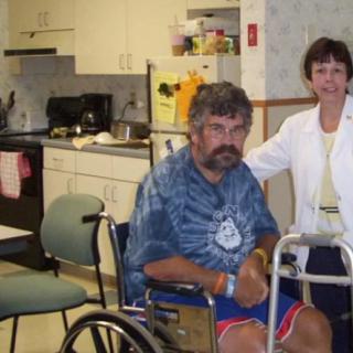 A man in a wheelchair and a woman in a healthcare setting.
