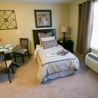 A cozy bedroom with a single bed, table, and chairs complemented by decorative wall art.