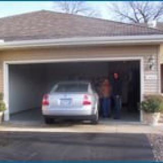 A car parked in a residential garage with two people standing inside.