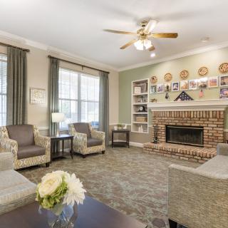 A cozy living room with comfortable seating, a brick fireplace, and large windows allowing natural light inside.