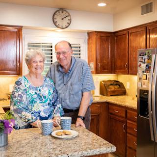 An elderly couple enjoys a moment together in their warm and welcoming kitchen.