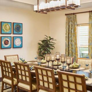 A well-decorated dining room with a large table, elegant chairs, and contemporary artwork on the walls.