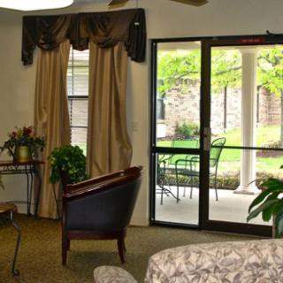A cozy living room with elegant curtains, a comfortable chair, and a view of the patio through glass doors.