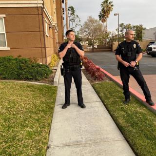 Two police officers standing on a sidewalk next to a building.