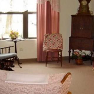A cozy living room with vintage furniture and soft pink curtains.