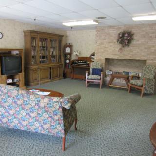 A cozy living room with a floral sofa, television, wooden cabinet, and carpeted flooring.