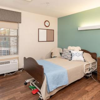 A well-furnished hospital patient room featuring a bed, medical equipment, and natural light.