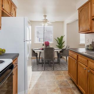 A cozy kitchen and dining area with wooden cabinets, modern appliances, and a small dining table with chairs by the window.
