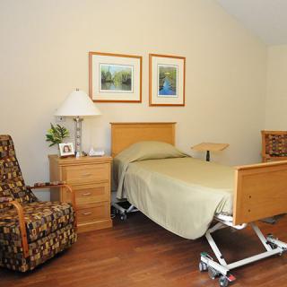 A well-organized hospital room with a bed, chair, and bedside table.