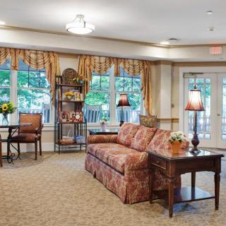 A cozy living room with a sofa, lamps, and large windows providing natural light.