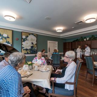 A group of elderly individuals socializing in a communal dining room.