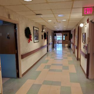 A well-lit corridor in a healthcare facility, featuring decorated doors and patterned flooring.