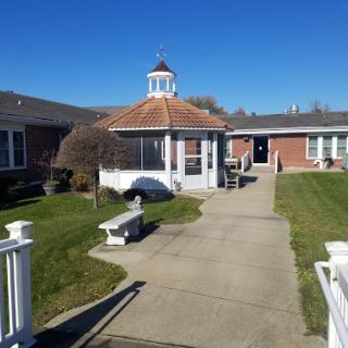 A serene outdoor courtyard featuring a gazebo, surrounded by well-maintained grass and pathways.