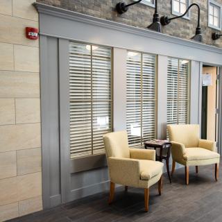 A cozy waiting area with two armchairs and a small table in front of large windows.