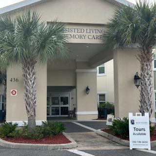 Entrance of a memory care facility with palm trees lining the pathway.