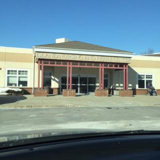 A storefront building on a sunny day with an empty parking lot in front.