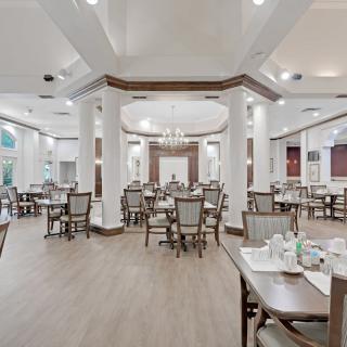 Elegant dining area with neatly arranged tables and chairs under bright chandeliers.