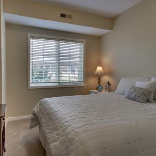 A cozy bedroom with a neatly made bed and a lamp by the window.