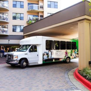A shuttle bus parked under the entrance of a hotel building.