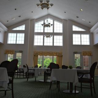 A spacious dining room with high ceilings, large windows, and elegantly arranged tables and chairs.