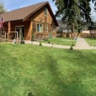 A charming wooden house with a well-maintained lawn and garden.