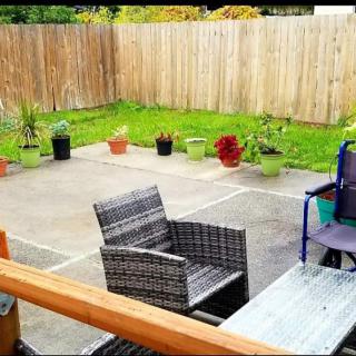 A cozy patio setup with chairs and potted plants, enclosed by a wooden fence.