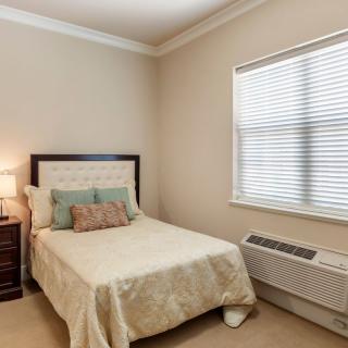 A cozy bedroom with a single bed, nightstand, and window.