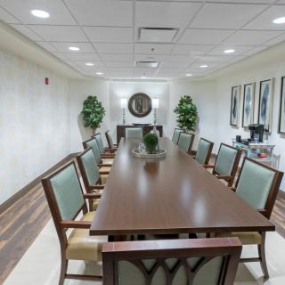 A conference room featuring a long meeting table with chairs, decorated with plants and artwork.