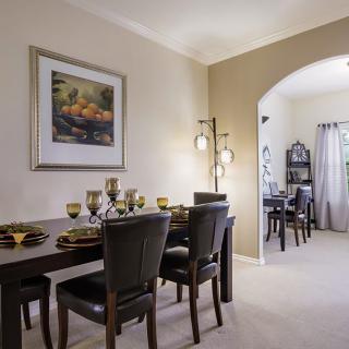 A modern dining room with a set table and elegant decor, featuring an archway leading to another room.