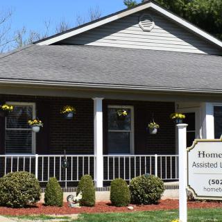 A charming house with a porch adorned with hanging flowers and a sign in front.