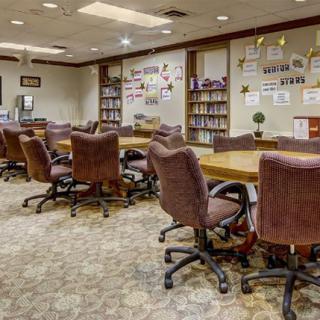 A spacious conference room with multiple tables and chairs, surrounded by bookshelves and decorated walls.