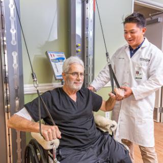 A healthcare professional assists a patient in a rehabilitation setting, showcasing the importance of support in physical therapy.