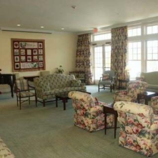 A cozy living room with floral-patterned furniture and large windows.