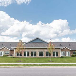 A residential building with a large lawn and a cloudy sky.