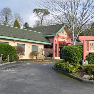 A Japanese-style restaurant with red pillars and a driveway, surrounded by well-kept landscaping.