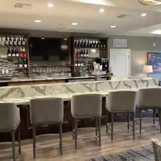 A modern bar interior with a marble countertop and neatly arranged stools.