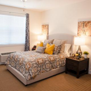 A cozy bedroom with a neatly made bed, decorative pillows, bedside lamps, and stylish curtains.