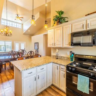 A modern kitchen with an open layout leading to a dining area, featuring granite countertops and pendant lighting.