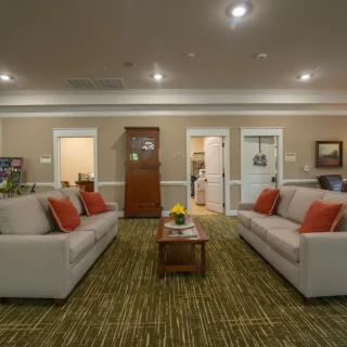 A cozy living room with two sofas facing each other, accented by orange pillows and a central coffee table.