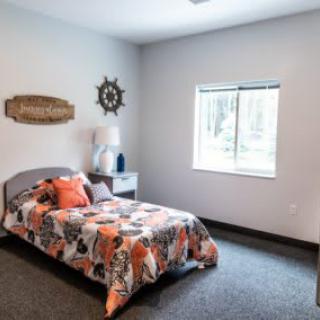 A cozy bedroom with a single bed, vibrant bedding, and decorative wall art.