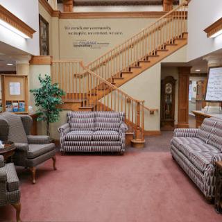 A cozy lobby area featuring comfortable sofas, a staircase, and decorative plants.