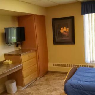 A cozy hotel room with a bed, television, and dresser.