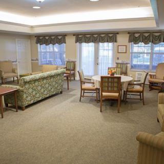 A cozy living room with sofas, chairs, and a round table surrounded by large windows.