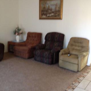 A cozy living room with a set of comfortable chairs lined up against the wall.