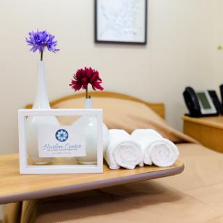 A welcoming bedside setup in a patient room featuring decorative flowers and neatly rolled towels.