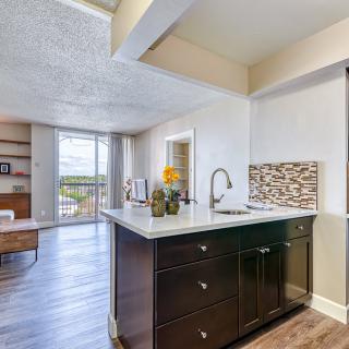 A modern open-concept kitchen with an island, adjacent to a cozy living area featuring hardwood floors and large windows.