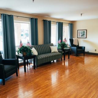 A well-lit living room with a sofa, chairs, and indoor plants on a hardwood floor.