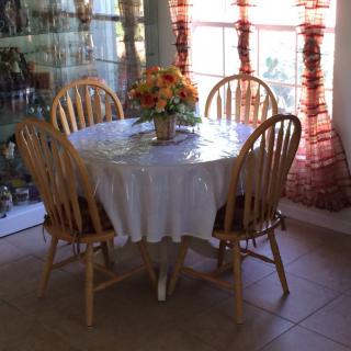 A cozy dining area with a round table and wooden chairs, adorned with a floral centerpiece.