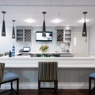 A modern bar area with striped chairs, pendant lights, and a mounted TV.